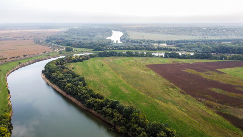 Aerial view of a river bending through farmland and riverside woodland